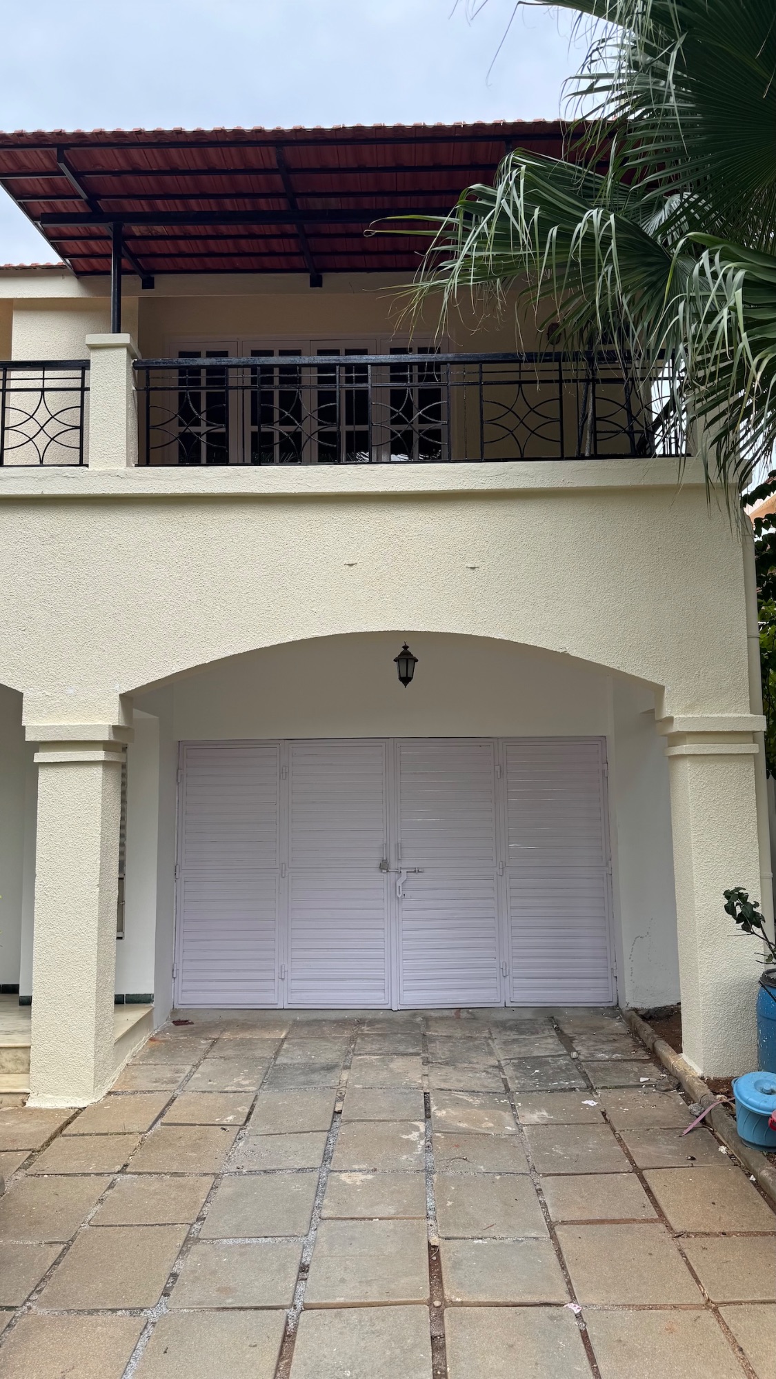 The garage under the first floor balcony, louvred doors shut.